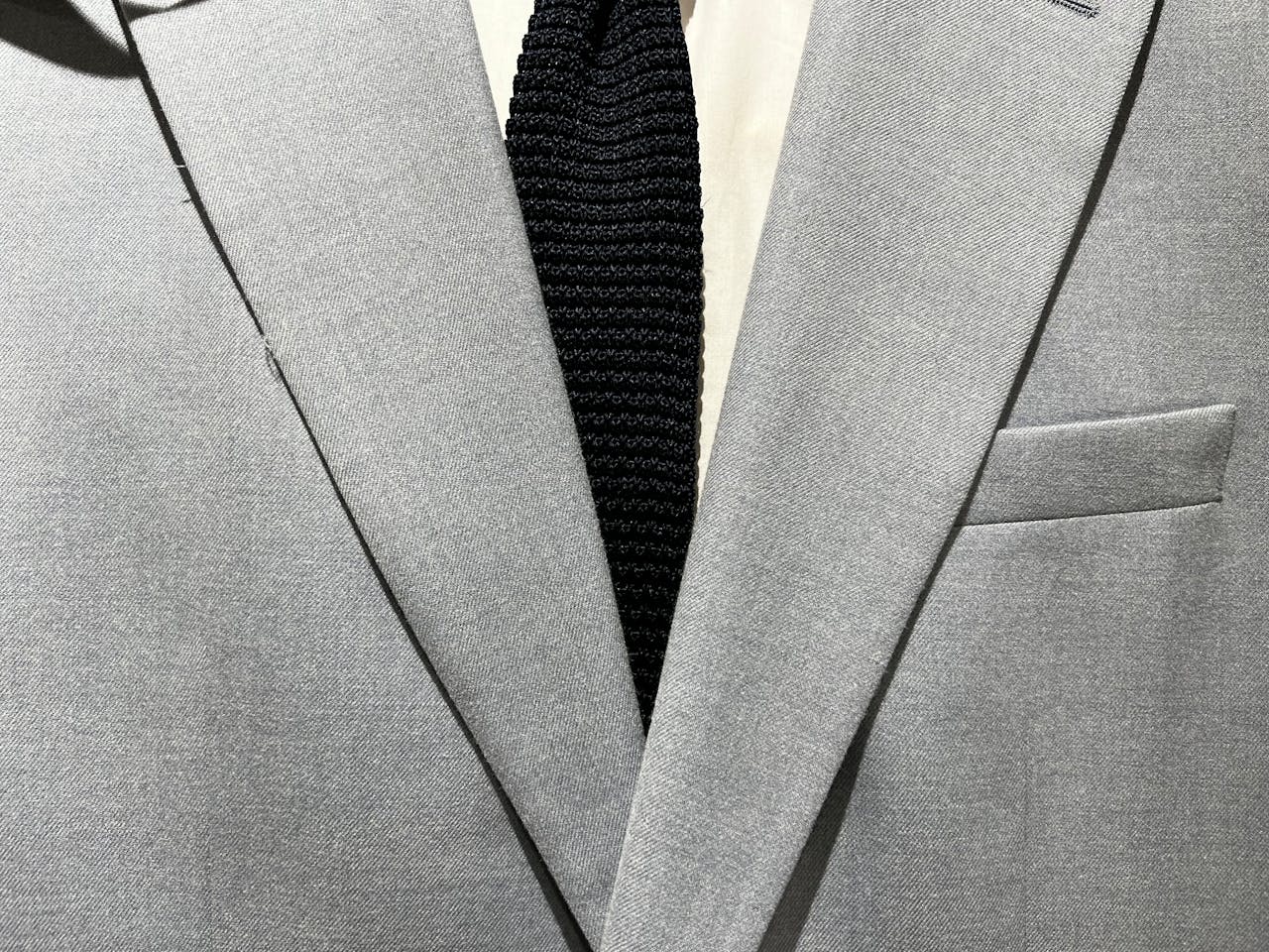 A sophisticated gray suit jacket and black tie combination showcasing formal fashion elegance.