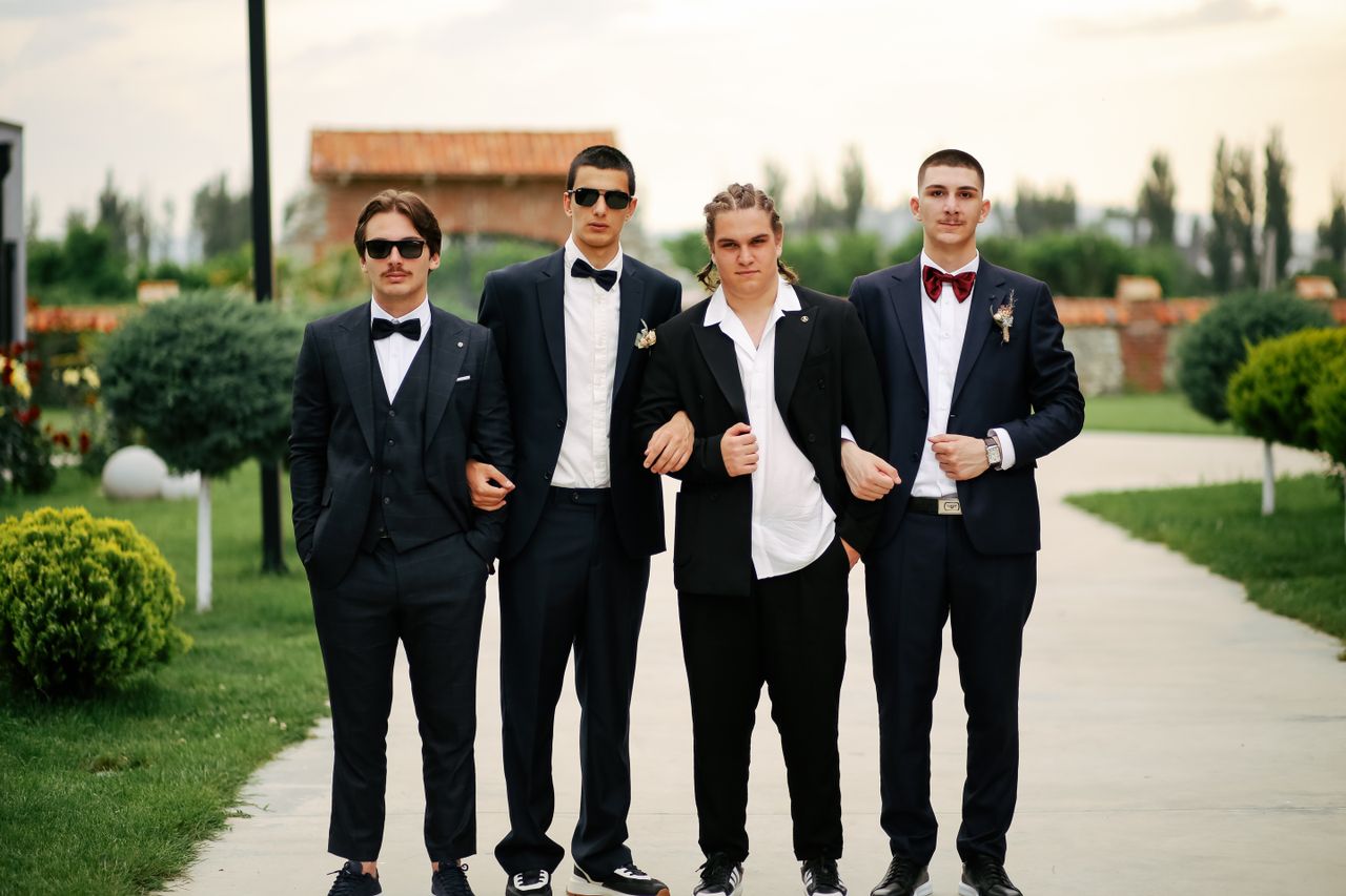 Group of well-dressed groomsmen posing outdoors in formal suits.
